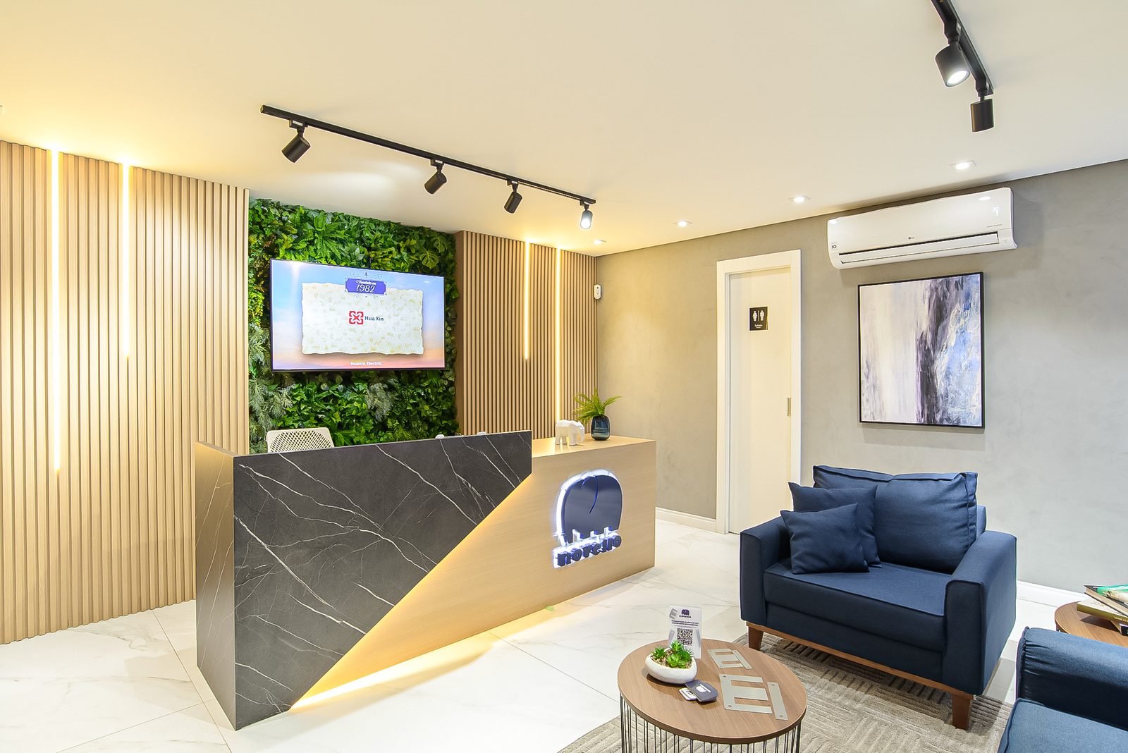 Recepção com jardim vertical e balcão iluminado no escritório Novello Importação e Exportação, projeto corporativo Studio Mies